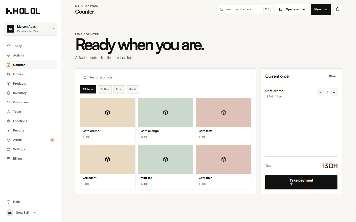 Holol POS counter with sample cafe products and an example current order; illustrative UI, not Cafe LM live data.